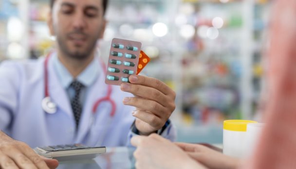 Man,Pharmacist,Holding,Medicine,Capsule,Blister,Pack,At,Counter,Dispensing